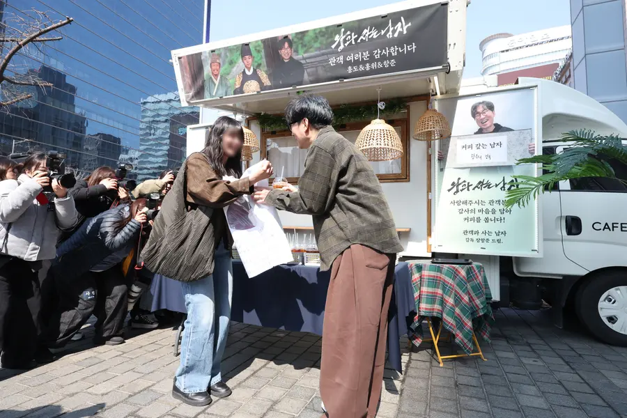 観客と会うチャン・ハンジュン監督 (ソウル=聯合ニュース) カン・ミンジ記者 = チャン・ハンジュン監督が12日、ソウル中区韓国プレスセンター広場で行われた映画『王と住む男』の興行感謝コーヒートラックイベントで市民にコーヒーを渡している。