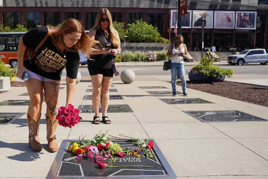 A citizen lays flowers at Dolly Parton’s memorial plaque on Nashville, Tennessee’s Music City Walk of Fame\n[Reuters-Yonhap. Not for resale or database use]